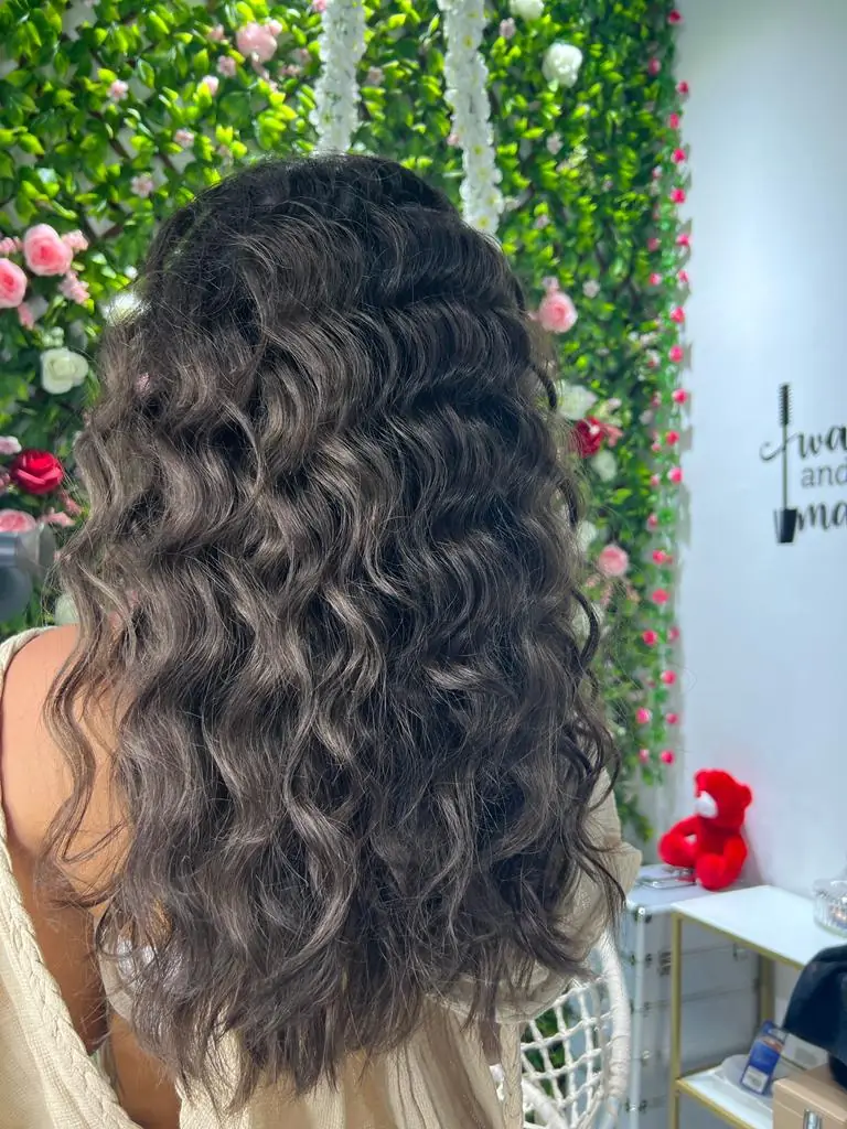 Soft curls in front of the salon's flower wall